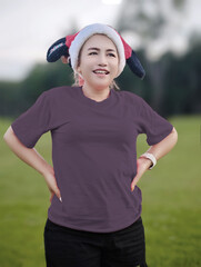 Young woman wearing Santa Claus hat and green t-shirt standing in the green field