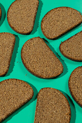 Pattern of dark rye bread slices on teal