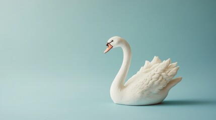 Naklejka premium A white swan figurine against a soft blue background, emphasizing elegance and tranquility.