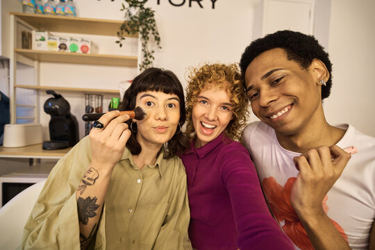 Three multiethnic friends applying makeup and having fun - Powered by Adobe