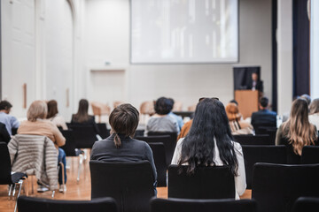 Speaker giving a talk in conference hall at business event. Rear view of unrecognizable people in audience at the conference hall. Business and entrepreneurship concept