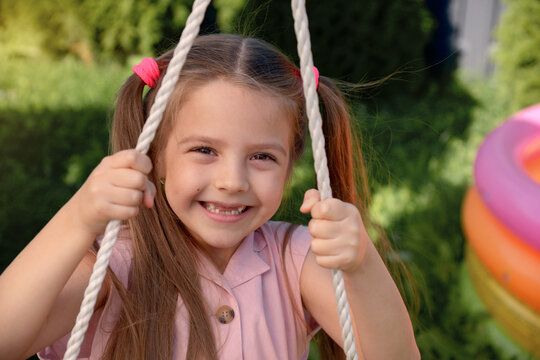 Joyful Child Swinging on a Playground Rope in Sunny Weather