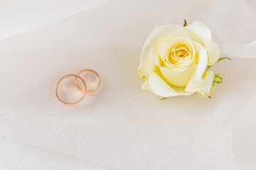 Elegant wedding rings on satin background with delicate flowers