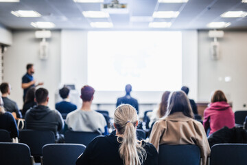 Speaker giving a talk in conference hall at business event. Rear view of unrecognizable people in audience at the conference hall. Business and entrepreneurship concept