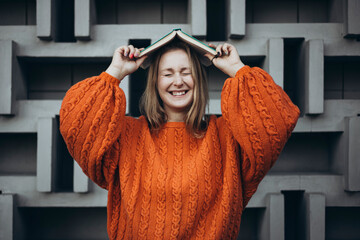 Female student smiling with a book against geometric wall background