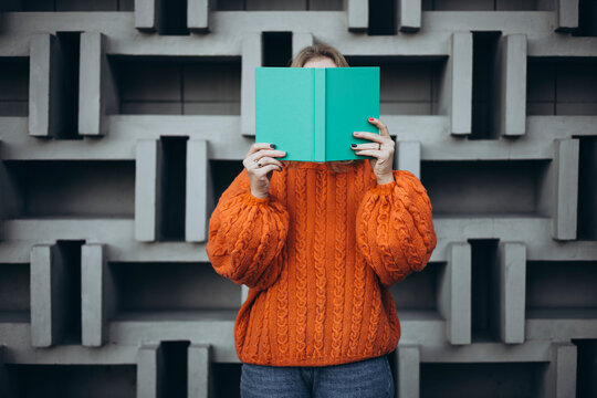 Female student reading book against geometric wall background
