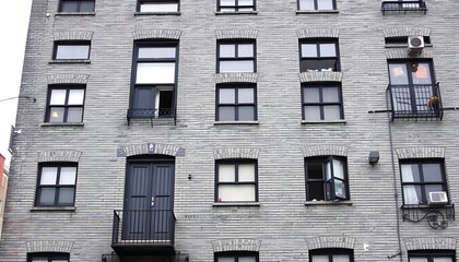 Obraz premium The classic gray brickwork of an older apartment building, with its sturdy, timeless architecture and character. 