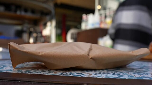 Waiter hands a pastry bag to customer in Spitalfields Market, London as coffee is being prepared