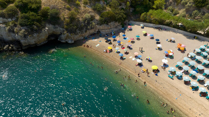 Aerial view of beach umbrellas on a sandy coast. A bay of the Mediterranean Sea with crystal clear and clean water.