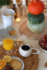 Pumpkins, various food and drinks, fall decorations, books and candles on the table. Fall hygge at home. Selective focus.