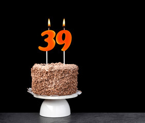 Birthday card with candle number 39 - Chocolate cake on black background.