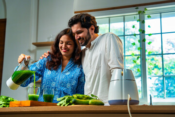 Obraz premium Indian wife serves fresh green spinach juice to her husband in kitchen, promoting healthy lifestyle