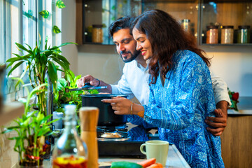 Couple standing by the stove, savoring the delicious aroma of steaming soup in a pot