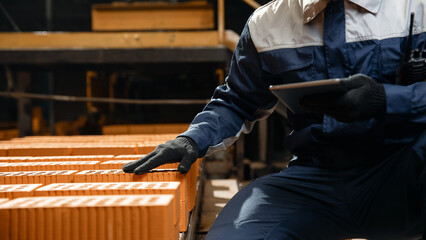 Portrait man worker holding tablet computer for control quality of bricks. Production line of ceramics factory