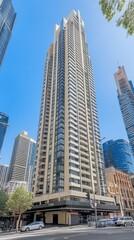 Fototapeta premium A tall modern skyscraper surrounded by other buildings in an urban setting.