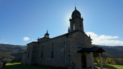 Side view of Alberguería church showing walls and bell tower, Galicia, Spain, in rural surroundings