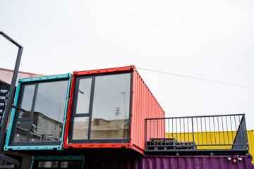 A vibrant and colorful shipping container that features a spacious balcony situated elegantly on its upper portion, adding a unique architectural touch to its design and usage
