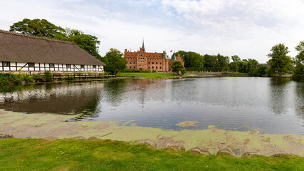 Fototapeta premium an panoramic outside view of the famous egeskov castle on a cloudy day in Denmark. 