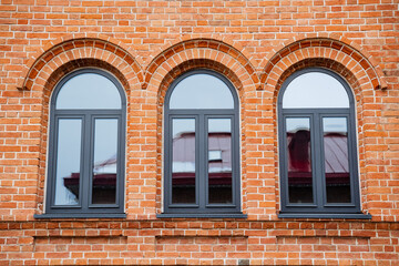 The striking red brick building features three elegantly arched windows, enhancing its architectural style and contributing to its stunning visual appeal and unique character