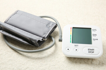 Blood pressure measuring device on light textured background, closeup
