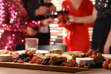 People clinking glasses of wine at party, focus on table with snacks