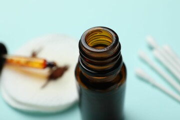Bottle of topical iodine, cotton pads and swabs on light blue background, selective focus