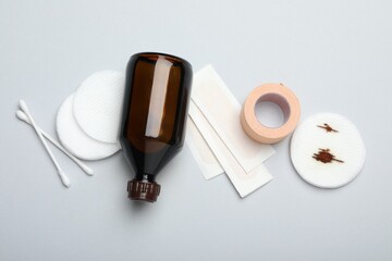 Topical iodine and other first aid kit components on light grey background, flat lay