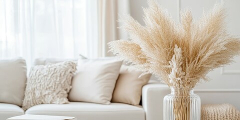 Stylish living room featuring white, beige, and gold furniture and decorations. This vertical photo showcases trendy monochrome design with dry pampas grass in a glass vase, highlighting neutral