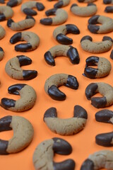 pattern out of home made nougat crescents cookies with chocolate at the edges on orange background 