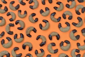 pattern out of home made nougat crescents cookies with chocolate at the edges on orange background 