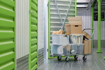 Background shot of cardboard boxes with personal belongings loaded on dolly cart in hallway of self...