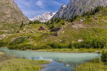 Val Veny scenic landscape in Courmayeur valley, Italy on Tour du Mont Blanc hiking route. Alps beautiful landscape, scenic view of the alpine peaks, green fields and meadow with flowers and blue sky