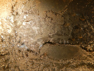 Natural hoarfrost on glass on frosty winter time - abstract background in shades of brown color....