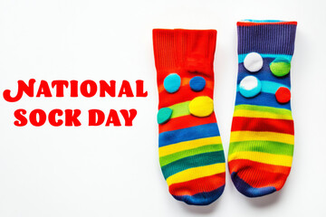 Two colorful striped socks decorated with pompoms alongside the bold red text "National Sock Day," celebrating fun and unique sock styles.