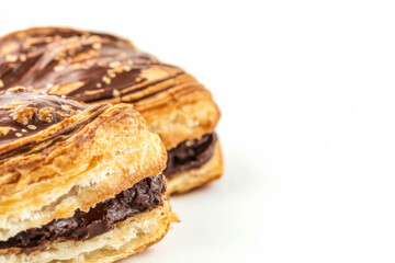 Close-up of a chocolate-filled pastry with flaky golden layers and sprinkled with sesame seeds on a clean white background. National Pastry Day.