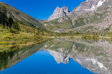 Val Veny scenic landscape in Courmayeur valley, Italy on Tour du Mont Blanc hiking route. Alps beautiful landscape, scenic view of the alpine peaks, green fields and meadow with flowers and blue sky