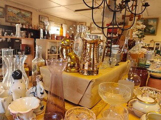 A variety of beautiful and vintage second-hand items displayed on shelves in a Swedish thrift store. A mix of flea market finds and garage sale treasures.
