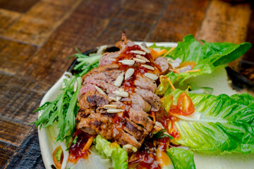 A flatlay shot of a beef salad topped with nuts and dressing, placed on a wooden table. The image also includes space for text, ideal for a customizable layout