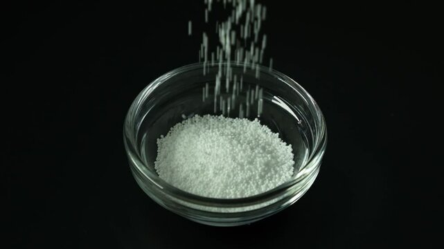 White crystalline powder is poured into a glass bowl. Video slow motion. Sodium benzoate, sodium salt of benzoic acid. Food additive E211. Food Preservative used in medicines and cosmetics.