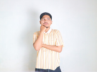 Thoughtful male customer thinking hard, looking away at copy space, leaning chin on hand. Handsome young man in strip polo shirt  standing isolated over white background. Special offer concept