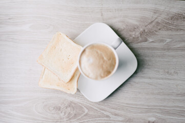 A white coffee cup with a white plate on top of it