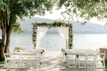 Elegant Lakeside Wedding Setup with Floral Arch and Scenic View  