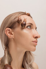 Beautiful young woman with snails on her face. Rejuvenation procedures