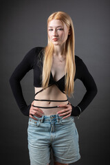 Portrait of a blonde woman with freckles in a sexy top and denim shorts in a studio.