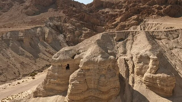 The caves and desert surrounding Qumran Nature Reserve, where the ancient Dead Sea Scrolls were discovered, on a dry summer day, highlighting their historic and sacred significance.