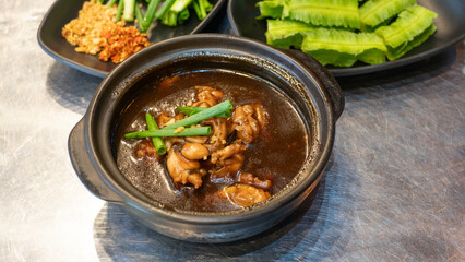 Eminent frog porridge or Singapore frog porridge and green onion in clay pot. Singapore braised frog and spring onion. Spicy frog porridge. 