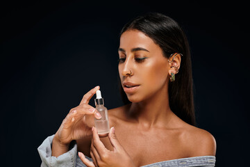 Obraz premium A beautiful African American woman examines a skincare serum in a studio environment.