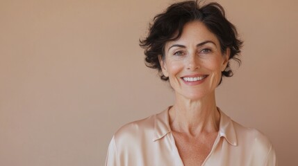 portrait of a smiling 50 year old beautiful woman with natural makeup in a silk robe on a beige background, beauty and skin care concept,  anti age