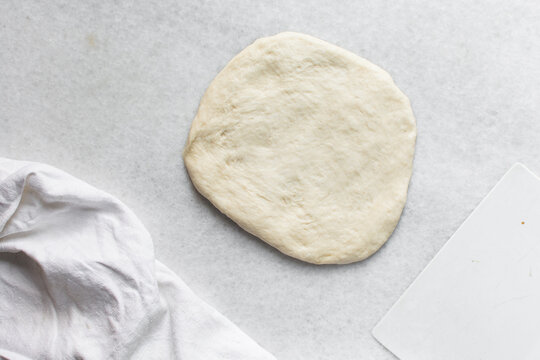 Overhead view of challah dough being shaped on a white granite countertop, top view of homemade challah bread dough on white countertop, process of making challah