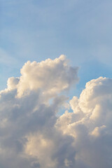 Soft, fluffy clouds illuminated by sunlight against a blue sky, creating a serene and peaceful atmosphere in a natural setting